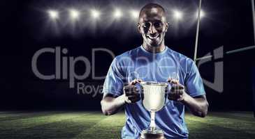 Composite image of portrait of happy athlete holding trophy