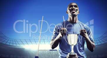 Composite image of happy athlete holding trophy looking up