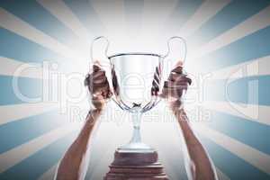 Composite image of cropped hand of athlete holding trophy