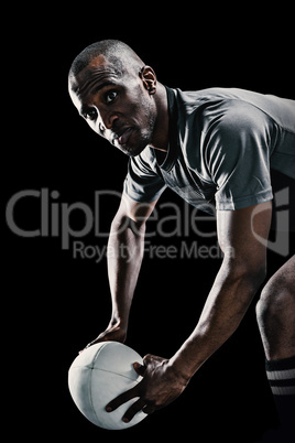 Composite image of rugby player looking away while holding ball