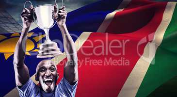 Composite image of happy athlete cheering while holding trophy
