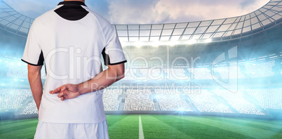 Composite image of rear view of rugby player with fingers crossed