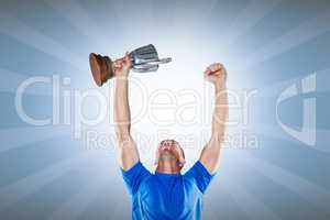 Composite image of happy rugby player holding trophy