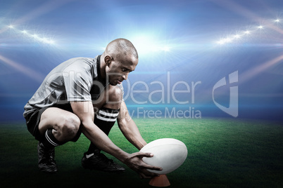 Composite image of rugby player keeping ball on kicking tee