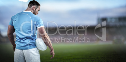 Composite image of rugby player standing with ball