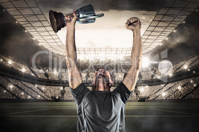 Composite image of happy rugby player holding trophy