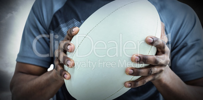 Composite image of mid section of sportsman holding rugby ball