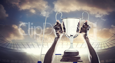 Composite image of cropped hand of athlete holding trophy