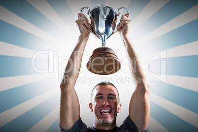 Composite image of portrait of successful rugby player holding t