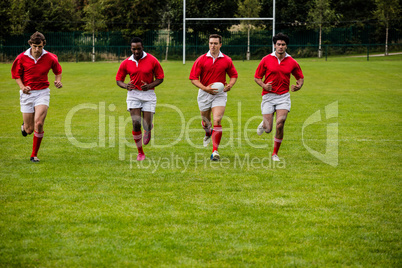 Rugby players jogging with ball