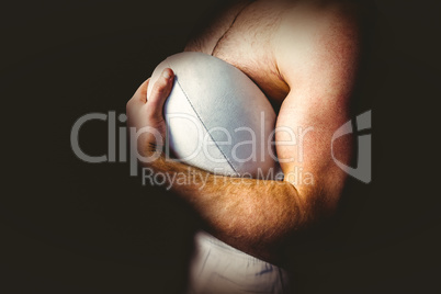 Shirtless rugby player holding ball