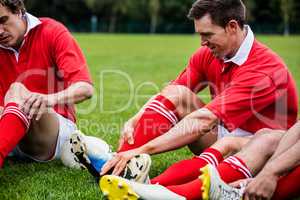 Rugby players sitting on grass before match