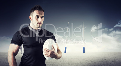 Composite image of tough rugby player holding ball