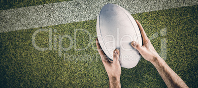 Composite image of a rugby player posing a rugby ball