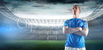 Composite image of serious rugby player looking away with arms crossed