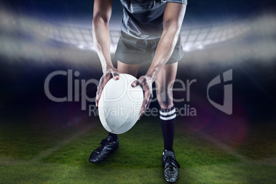 Composite image of low section of athlete holding rugby ball