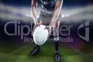 Composite image of low section of athlete holding rugby ball
