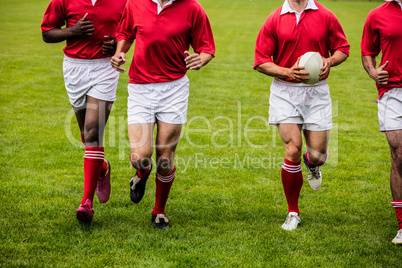 Rugby players jogging with ball