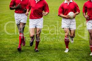 Rugby players jogging with ball