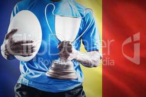 Composite image of mid section of sportsman holding trophy and r
