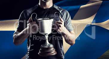 Composite image of victorious rugby player holding trophy