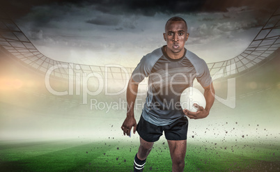 Composite image of portrait of determined sportsman holding rugb