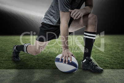 Composite image of rugby player in black jersey stretching with ball
