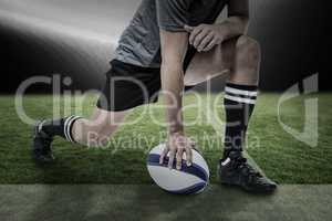 Composite image of rugby player in black jersey stretching with ball