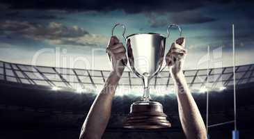 Composite image of successful rugby player holding trophy