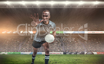 Composite image of aggressive rugby player gesturing while holdi