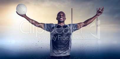 Composite image of confident athlete with arms raised holding rugby ball