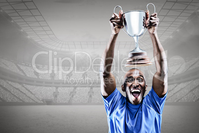 Composite image of happy athlete cheering while holding trophy