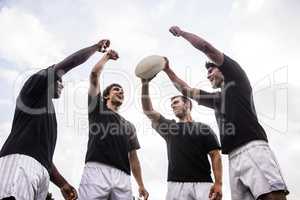 Rugby players cheering together with ball