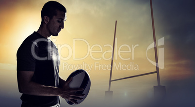 Composite image of calm rugby player thinking while holding ball