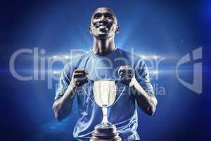 Composite image of happy athlete holding trophy looking up