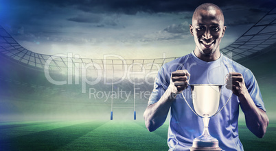 Composite image of portrait of happy sportsman holding trophy