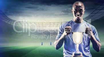 Composite image of portrait of happy sportsman holding trophy