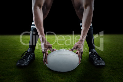 Composite image of low section of sportsman holding ball while playing rugby