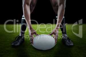 Composite image of low section of sportsman holding ball while playing rugby