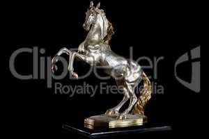 Classic painted gold marble statuette of bucking horse isolated on black background