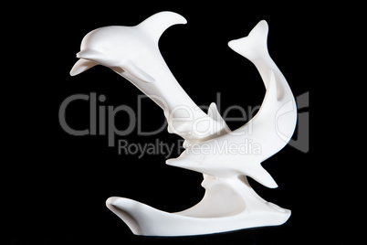 Classic white marble statuette of 2 dolphins isolated on black background