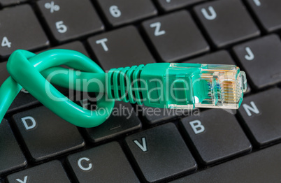 Netzwerkkabel grün mit Knoten und Tastatur
