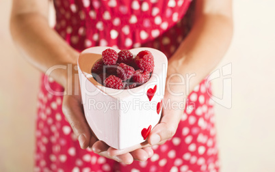 Woman holding a cup of raspberries