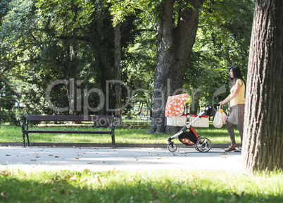 Mother walking in the park with baby buggy