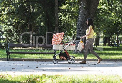 Mother walking in the park with baby buggy