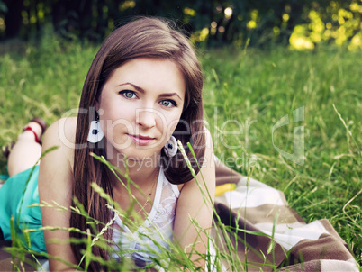 Young sensual smiling blonde lying on the grass in the sunlight