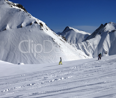 Snowboarders downhill on off piste slope at sun day