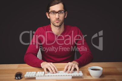 Serious man typing on keyboard with coffee on desk