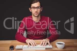 Serious man typing on keyboard with coffee on desk