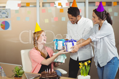 Smiling colleagues giving birthday gifts